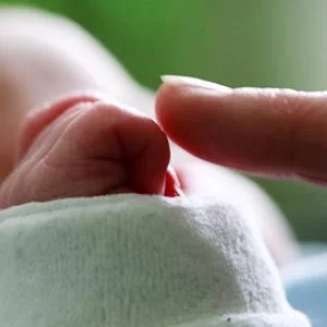 ein Zeigefinger berührt die Hand eines Babys