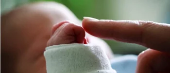 ein Zeigefinger berührt die Hand eines Babys