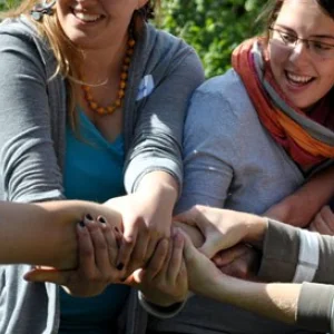 viele lachende Menschen ziehen zusammen an einem Arm